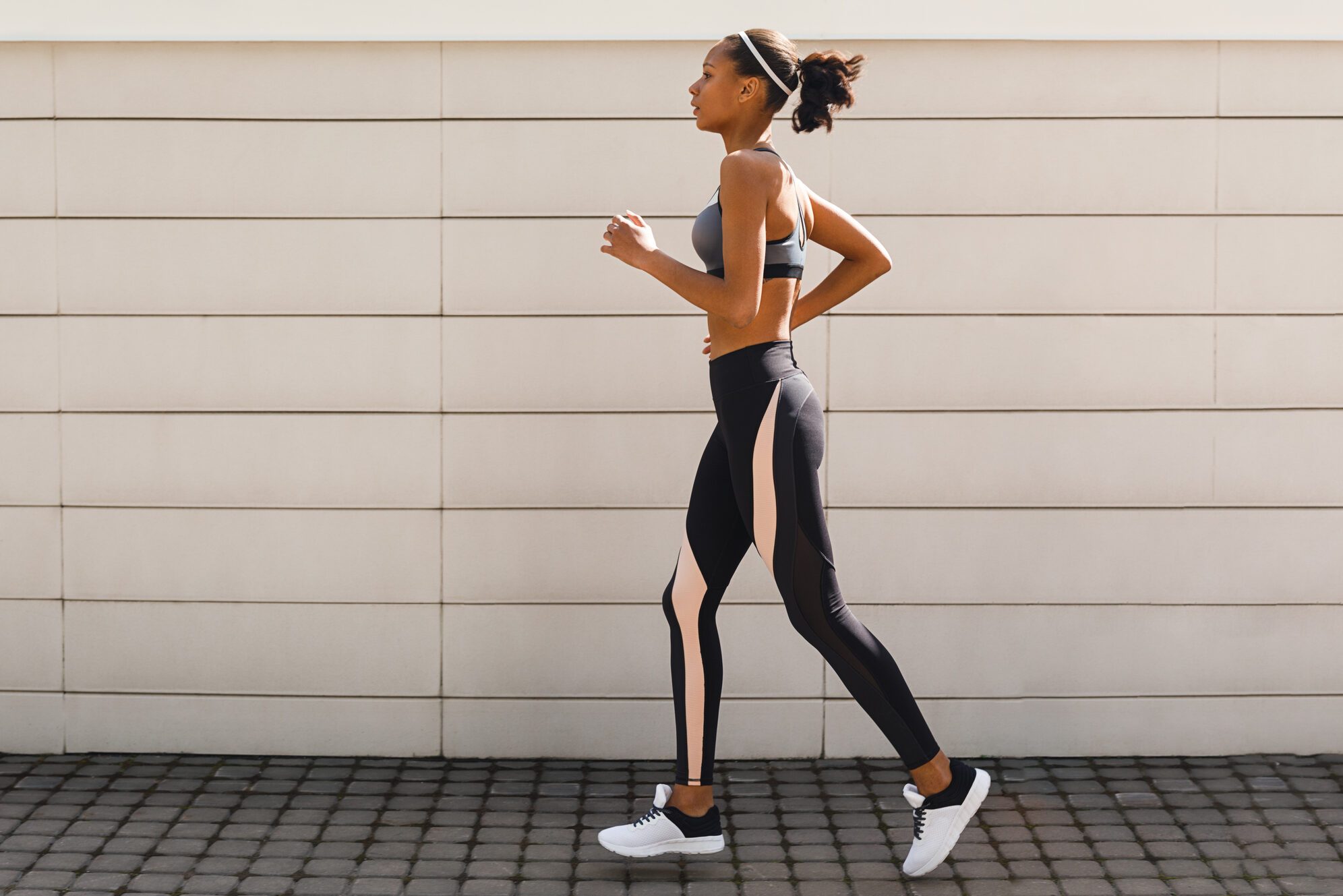 Young woman jogging near a wall, side view