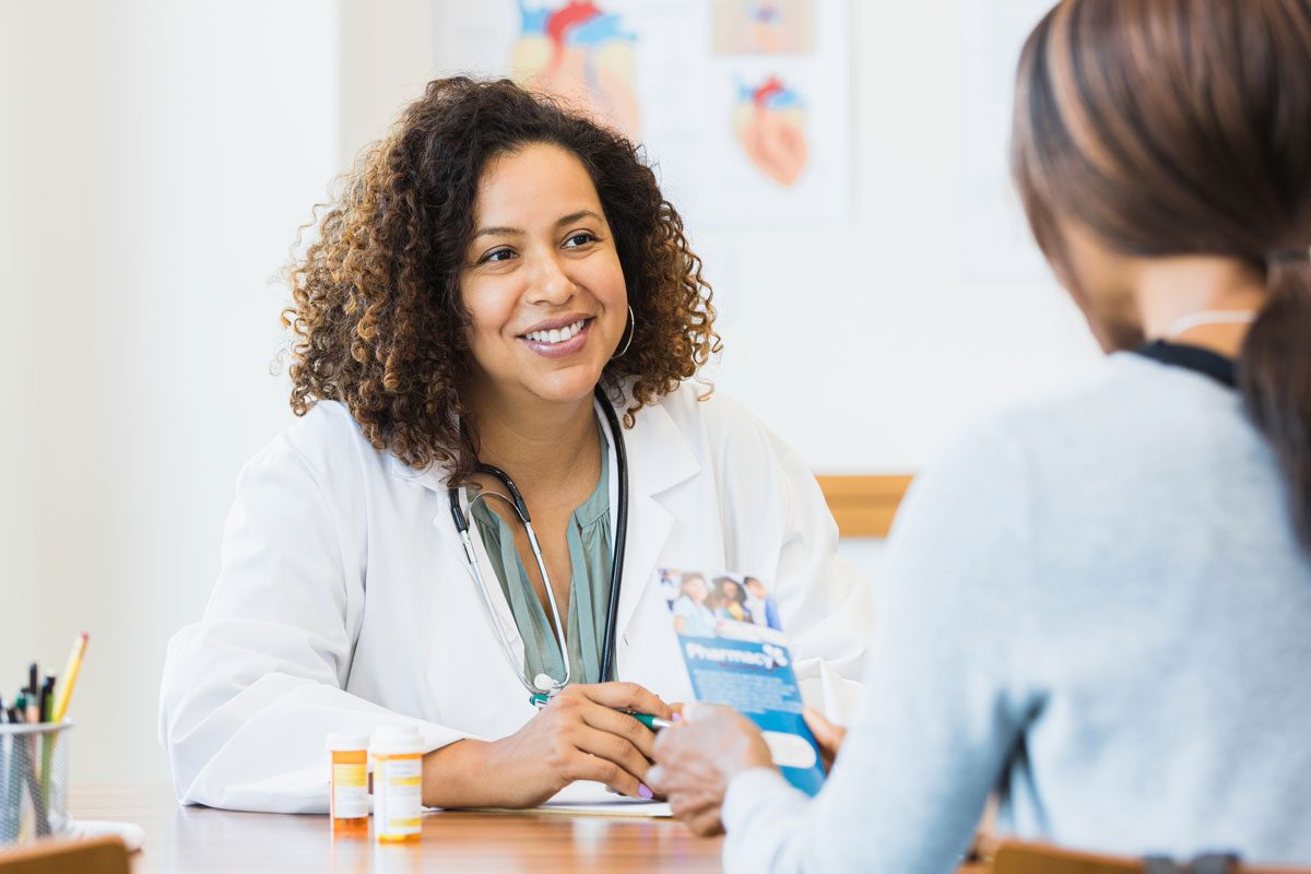 Female Doctor Smiles And Listens To Unrecognizable Female Patient