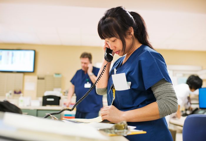 Nurse checks notes while talking on phone