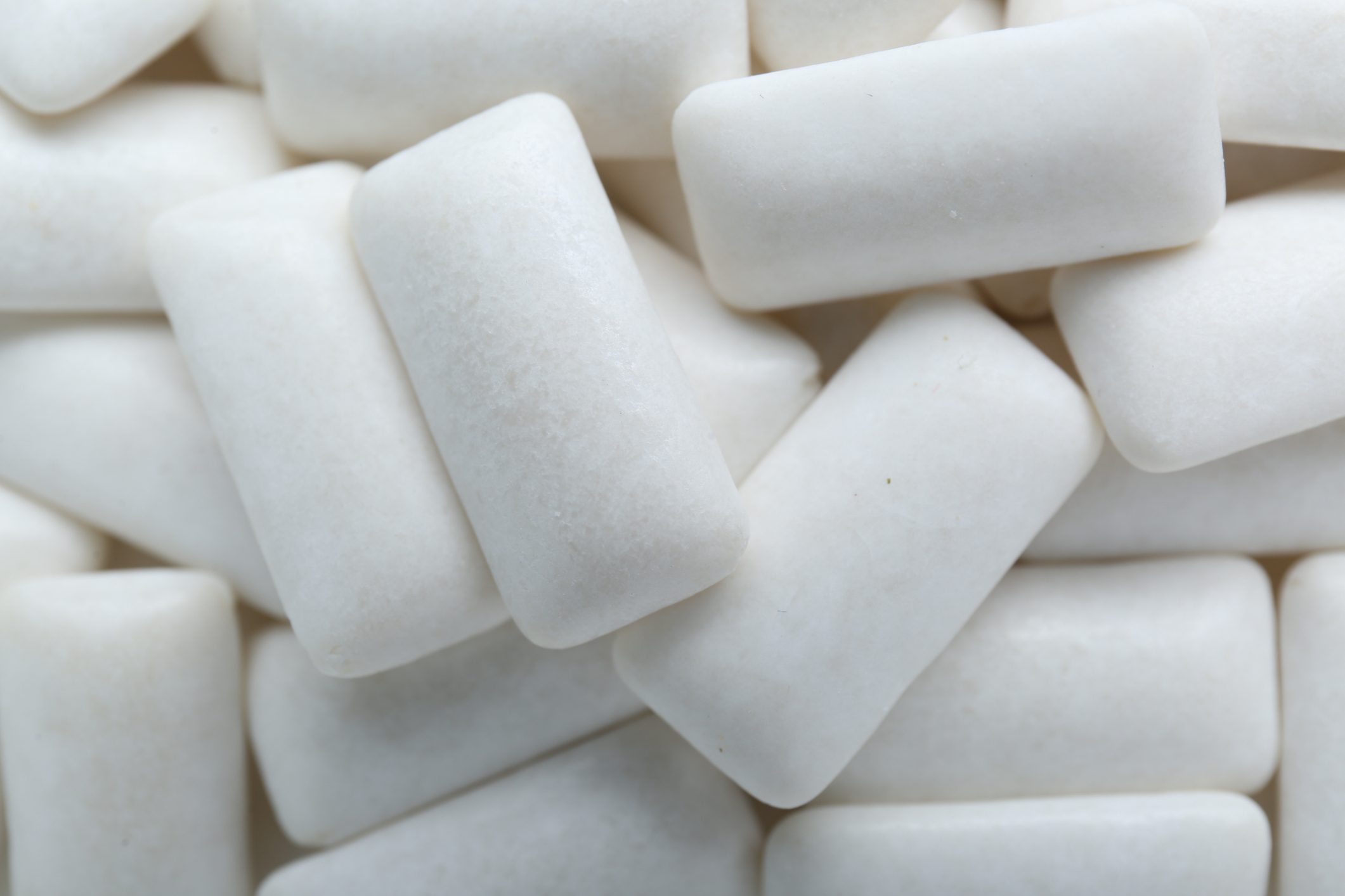 Tasty white chewing gums as background, top view