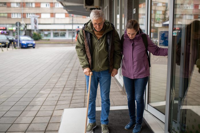Woman helping a senior man leave a hospital