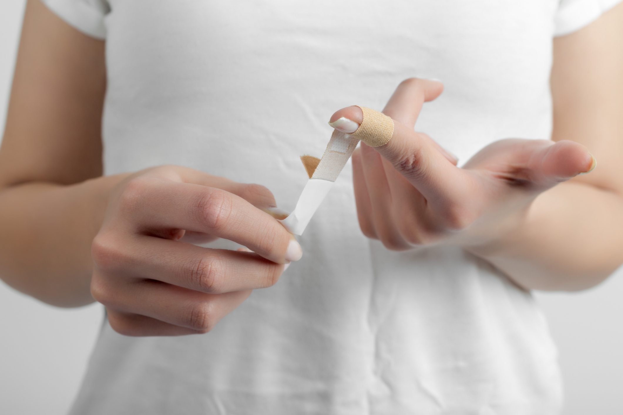 Hand putting a plaster on wounded finger