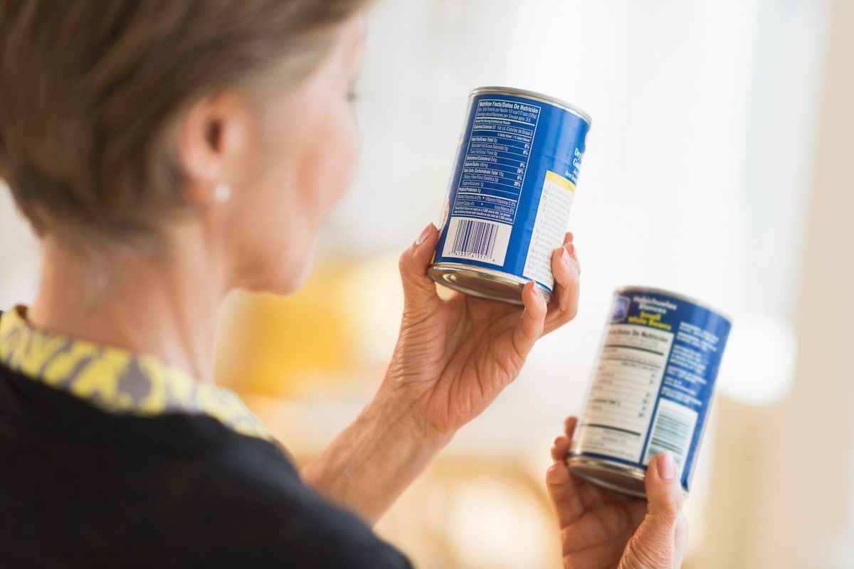 woman checking labels on food cans