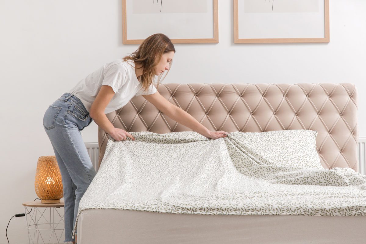 Woman Changing Bed Linens At Home
