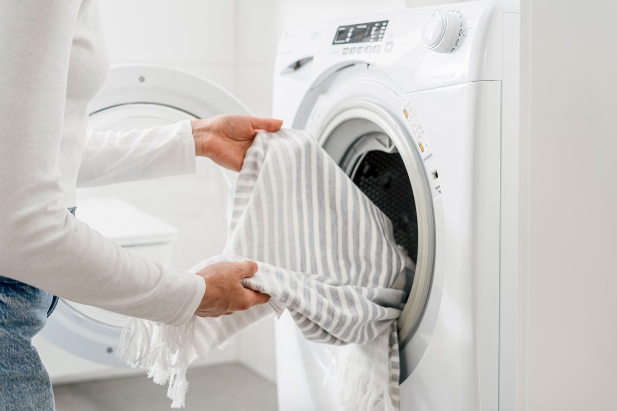 Woman Load Dirty Clothes In Washing Machine