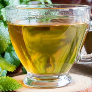 A Cup Of Melissa (lemon Balm) Tea On A Table With Fresh Melissa Leaves