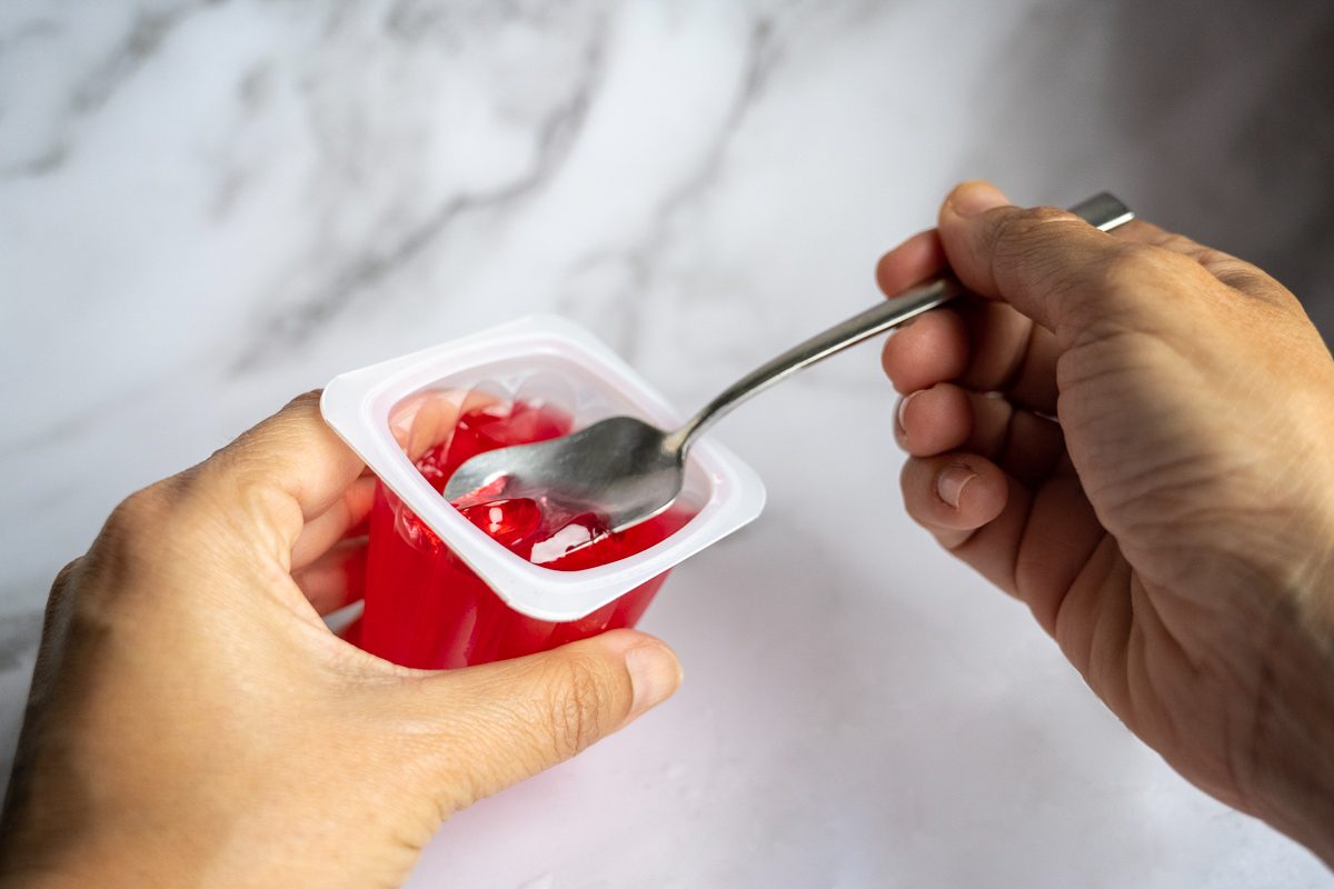 person eating red gelatin with spoon