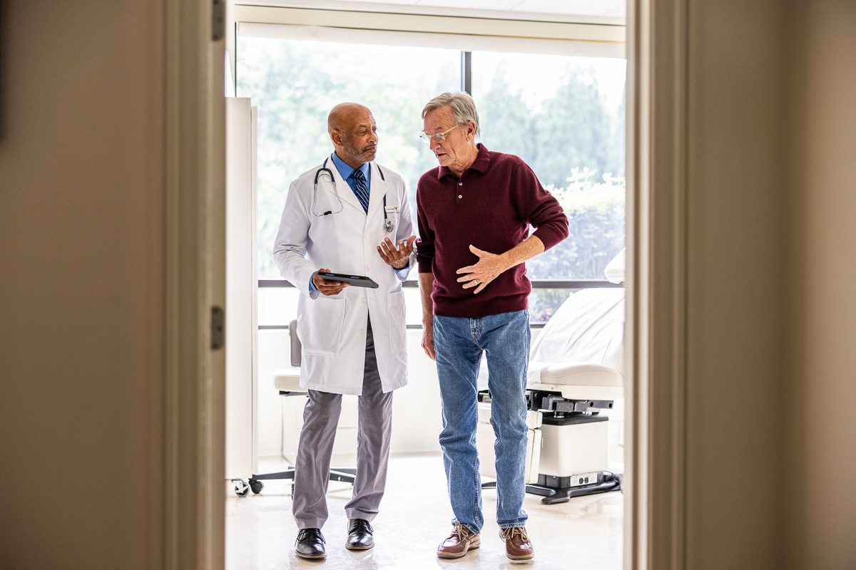 old man talking to male doctor in examination room